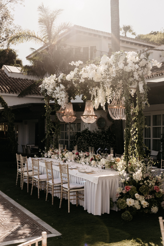 Luxe dinertafel in Marbella voor de bruiloft van Peter & Lotta – gedekte tafel met veel bloemwerk en gouden stoelen, verzorgd door weddingplanner in Spanje